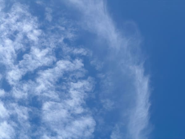 A sweeping band of textured white clouds against blue.