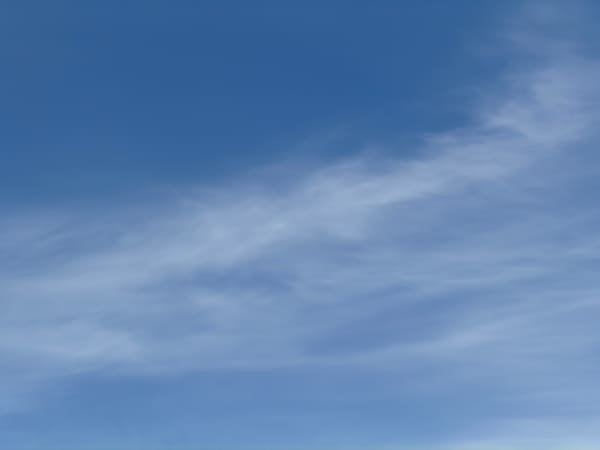Thin, pale clouds drifting across a blue sky.