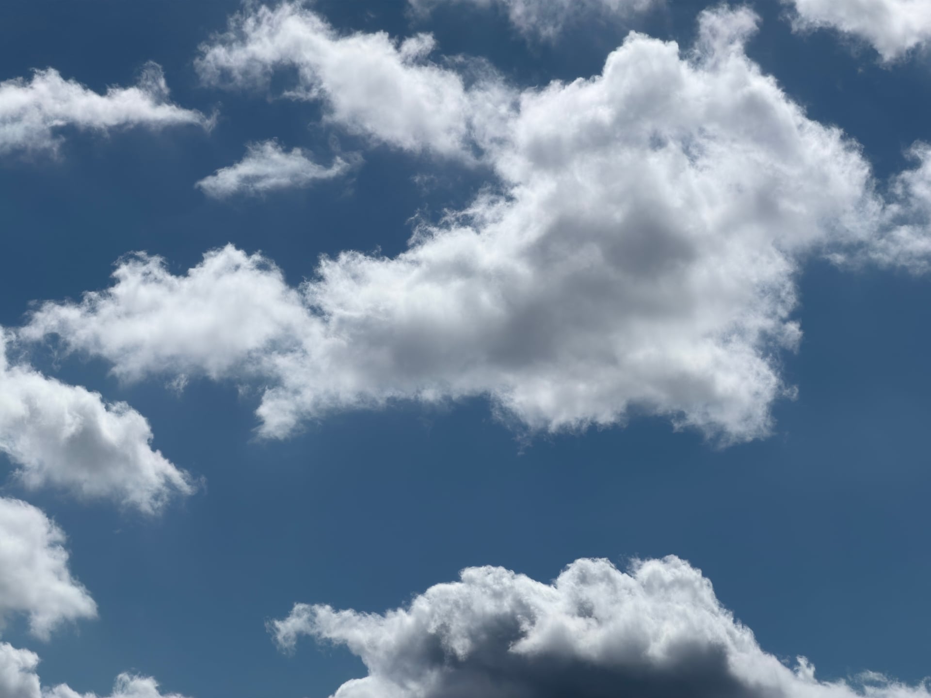 Bright cumulus clouds against a deep blue sky.