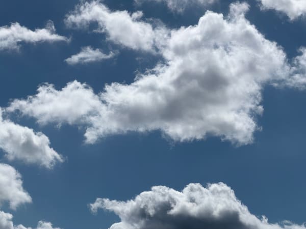 Bright cumulus clouds against a deep blue sky.